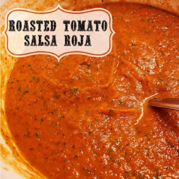 Overhead view of a large bowl full of roasted tomato salsa roja with a spoon in it.