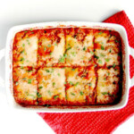 Zucchini pizza casserole in a white casserole dish on a red dish towel.