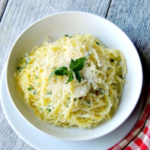 Herbed spaghetti squash with parmesan cheese in a white bowl on a wooden table.