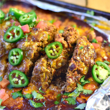 Low carb taco meatloaf topped with sliced jalapenos on a foil lined baking sheet.