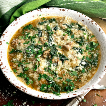 Low carb white chicken chili topped with fresh grated parmesan cheese and parsley in a white bowl on a wooden table.
