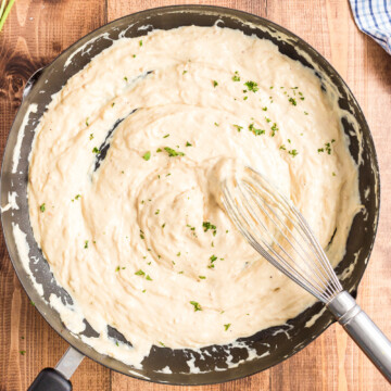 Copycat Olive Garden Alfredo Sauce (Low Carb) in a skillet on a wooden table.