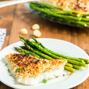 Oven Baked Coconut Macadamia Fish Fillets on a white plate with asparagus.