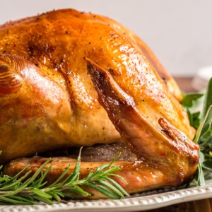 Closeup of golden-brown crispy-skinned roast turkey, ready to serve and enjoy.
