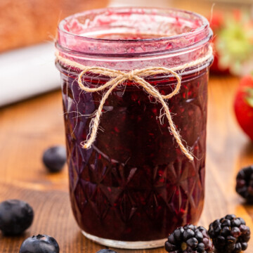 Keto mixed berry jam in a glass jelly jar with a jute bow.