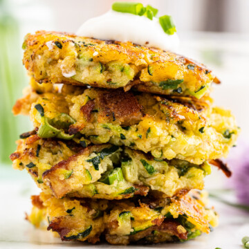 Keto Zucchini Fritters with Bacon and Cheese stacked on a white plate.