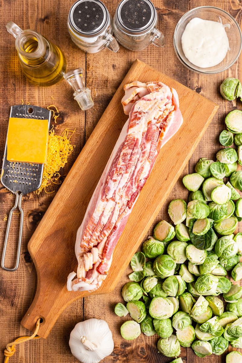 Overhead photo of ingredients for Cheesy Bacon Ranch Brussels Sprouts on a wooden tabe.