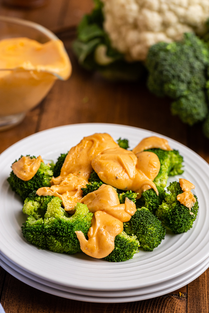 Close up photo of Easy Keto Cheese Sauce over broccoli on a white plate.