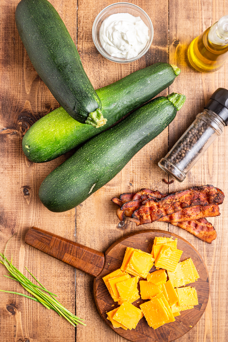 Overhead photo of the ingredients needed to make Hasselback Zucchini on a wooden table.