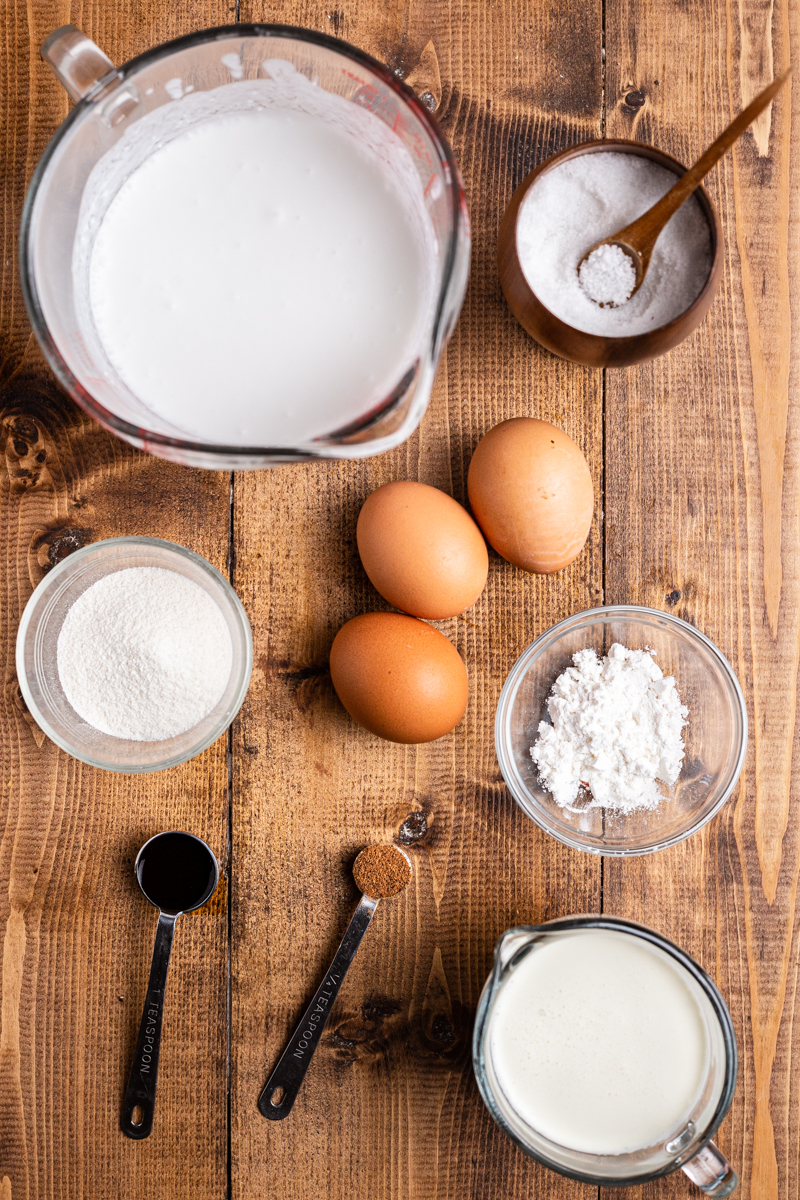 Over head photo of the ingredients needed to make Keto Eggnog (Dairy-Free & Sugar-Free) on a wooden table.