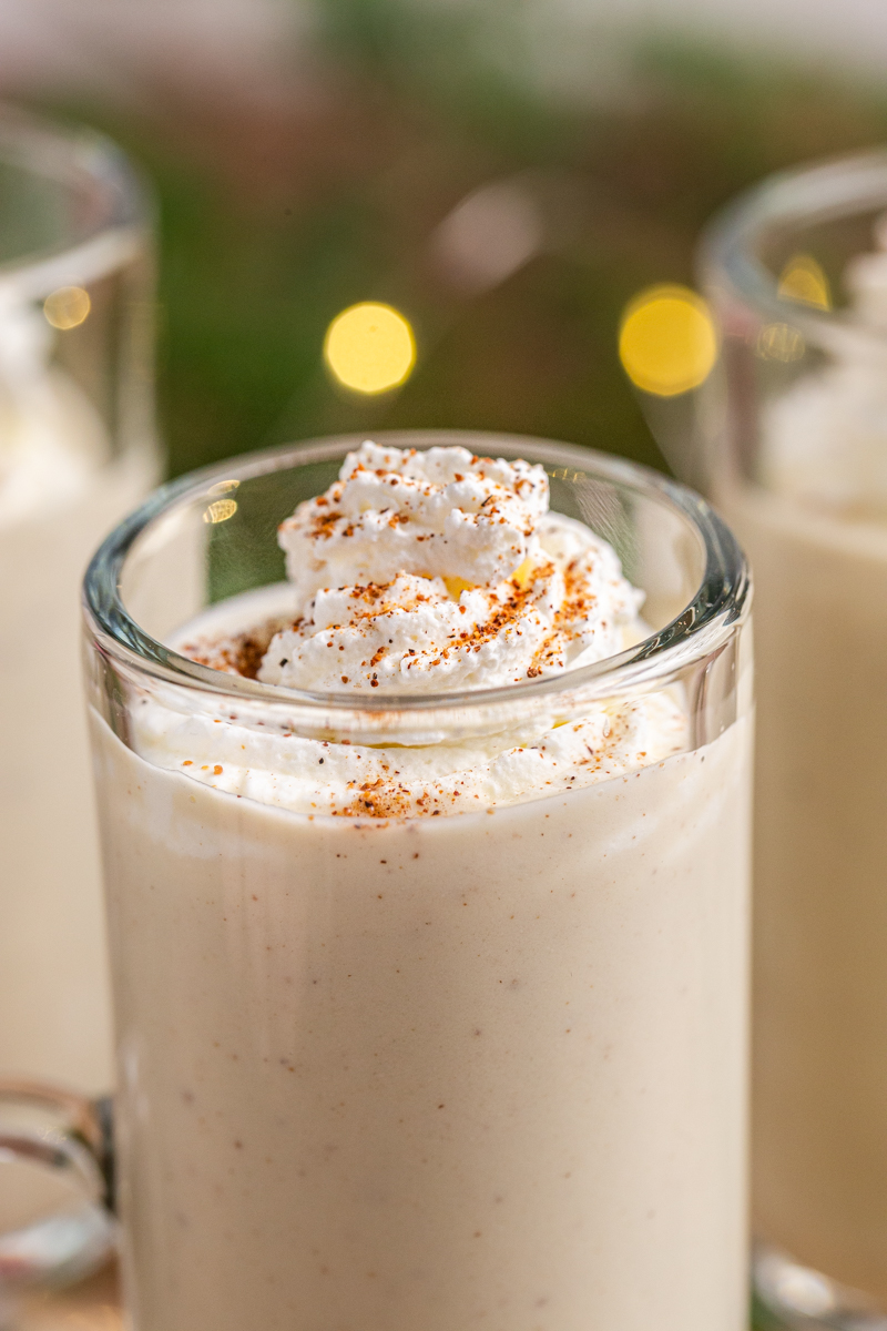 Closeup photo of Keto Eggnog in a glass mug with whipped coconut cream and nutmeg on top.