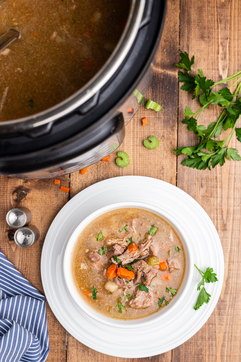 Overhead photo of Low Carb Instant Pot Pork Stew in the Instant pot and in a white bowl both on a wooden table.