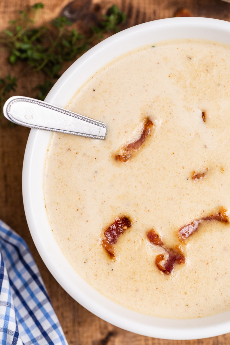Closeup overhead photo of Easy Cauliflower Cheese Soup in a white bowl with bacon sprinkled on top.