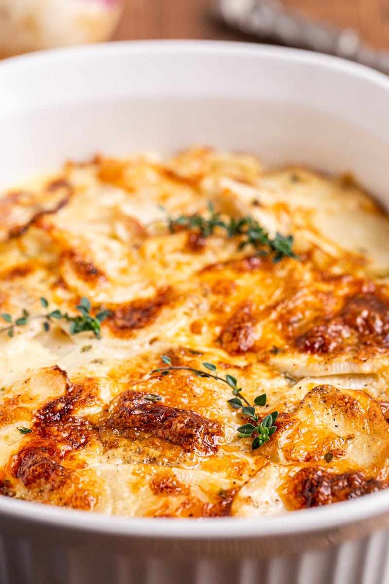 Close up photo of golden brown Turnips au Gratin in a white backing dish.