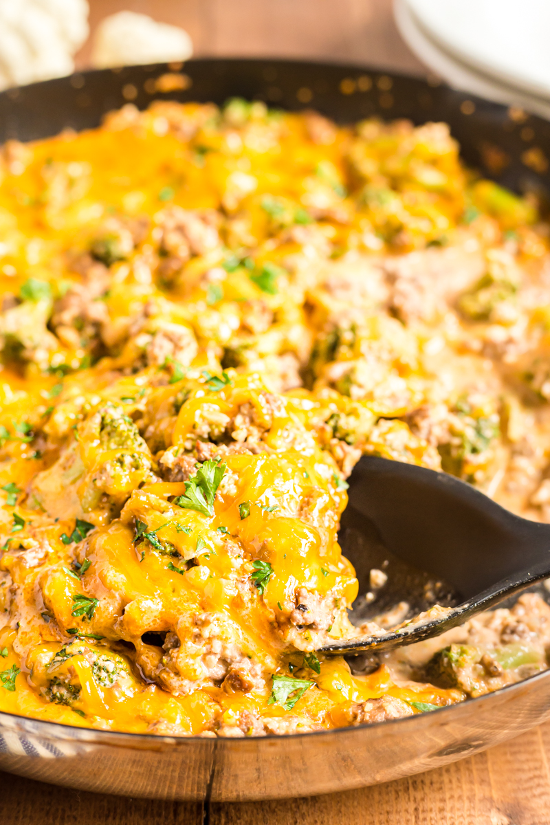 Closeup photo of Low Carb Cheesy Beef and Broccoli Rice Skillet in a skillet with a spoonful close to the camera.