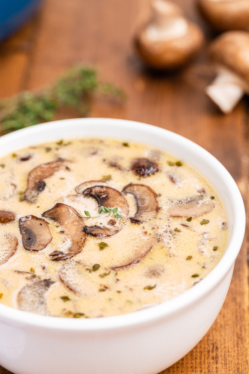 Close up photo of Keto Cream of Mushroom Soup in a white bowl on a wooden table.