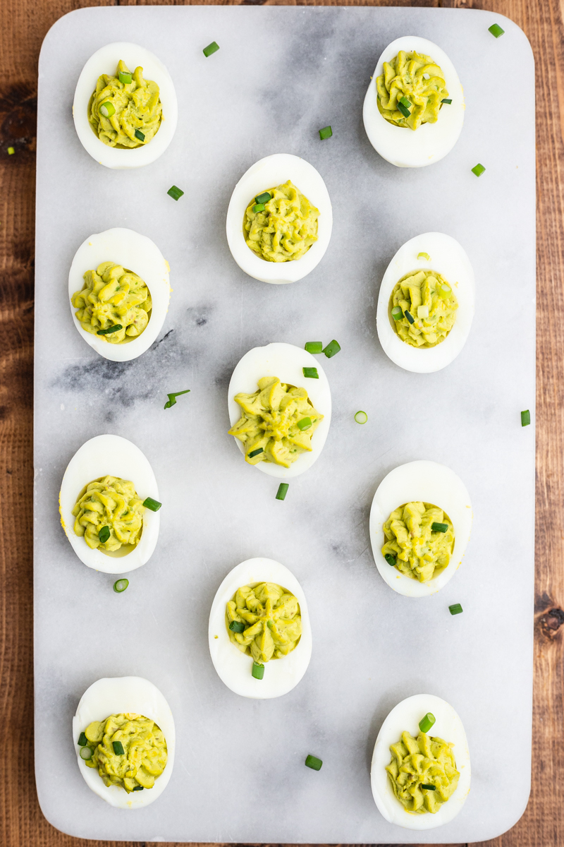 Overhead photo of Avocado Deviled Eggs on a marble background..