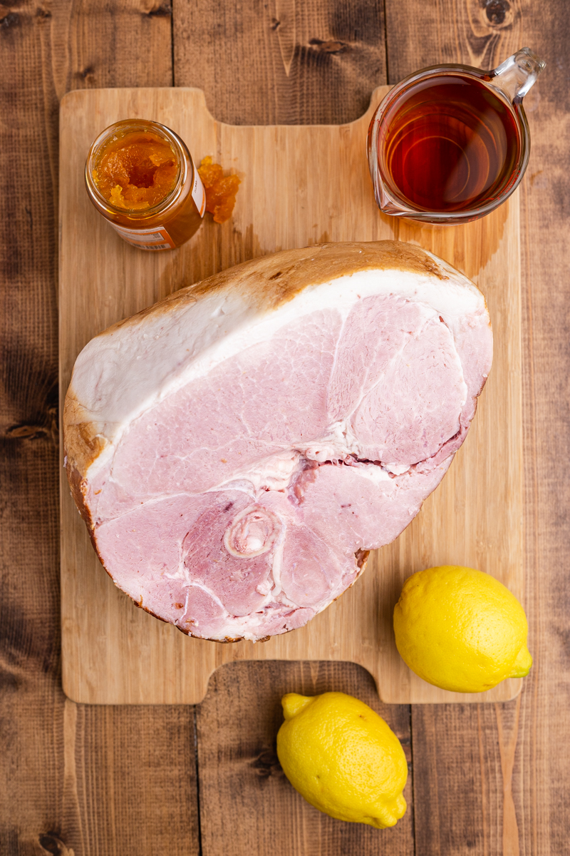 Overhead photo of the ingredients needed to make Keto Apricot Bourbon Glazed Ham on a wooden table.
