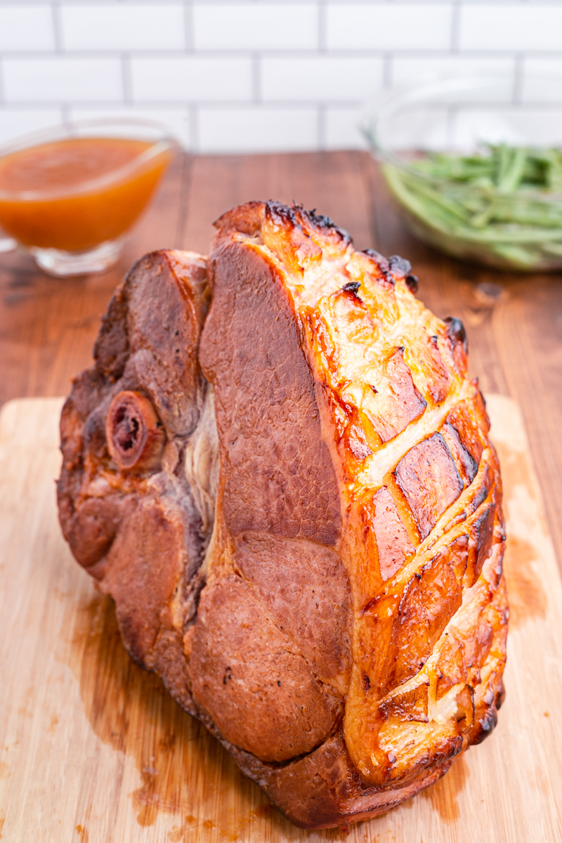 Photo of Keto Apricot Bourbon Glazed Ham on a wooden cutting board.