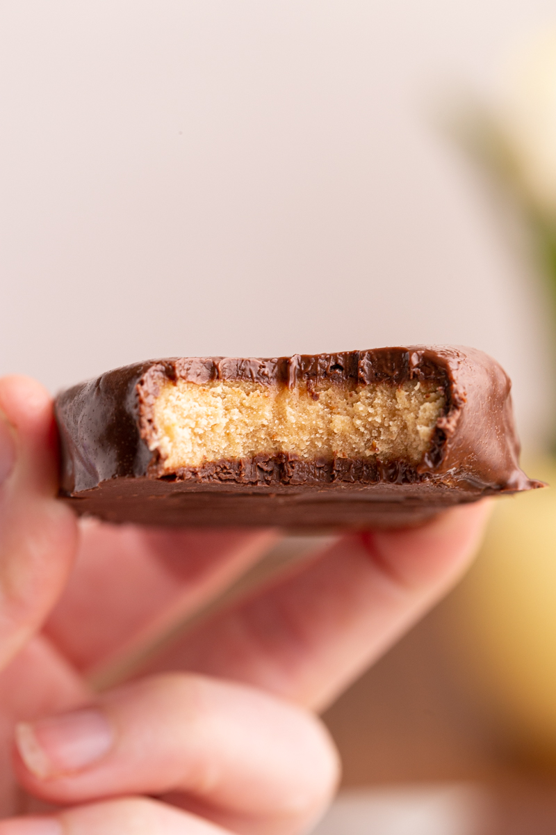 Closeup photo of someone holding a Keto Peanut Butter Chocolate Easter Egg with a bite taken out of it.