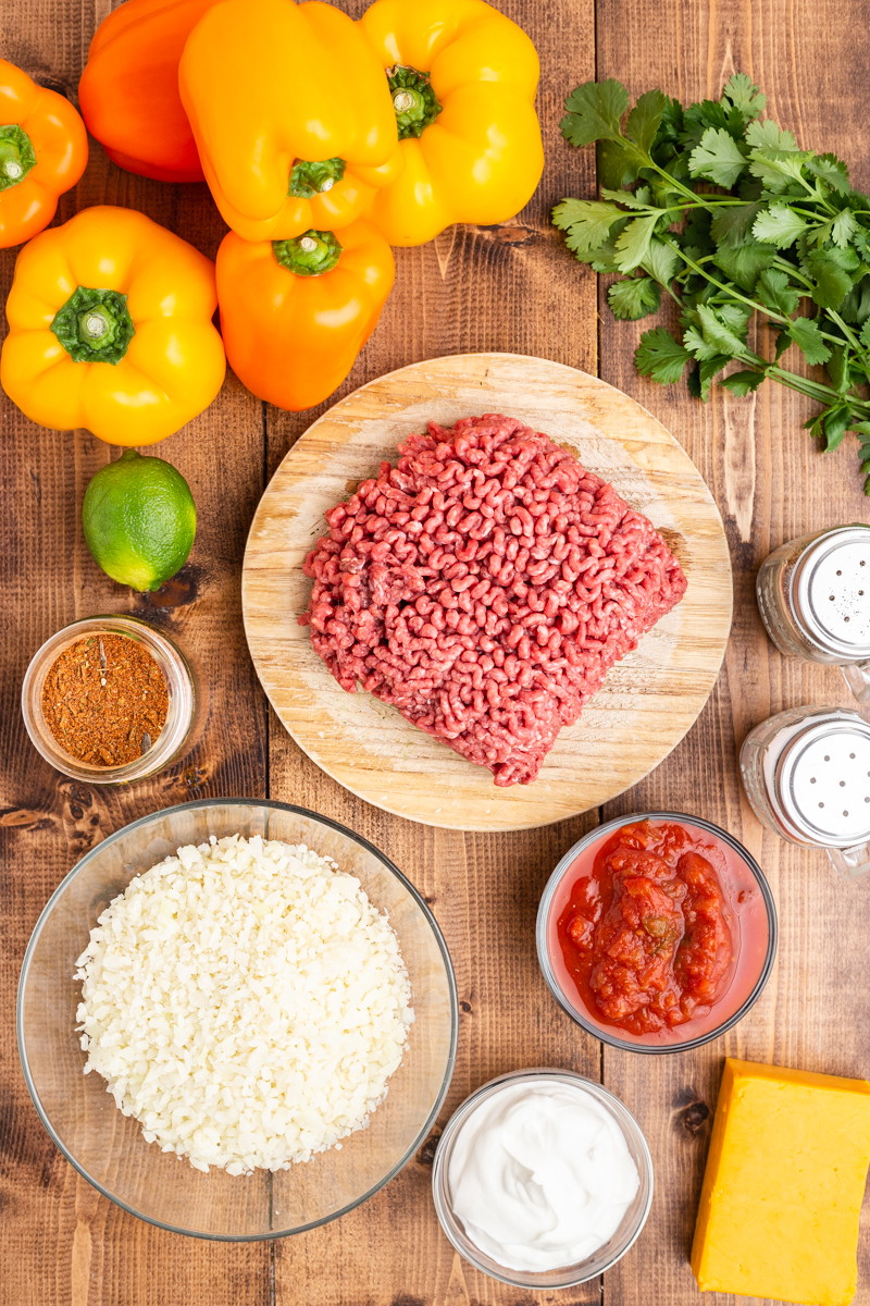 Overhead photo of the ingredients needed to make Keto Slow Cooker Mexican Stuffed Peppers on a wooden table.