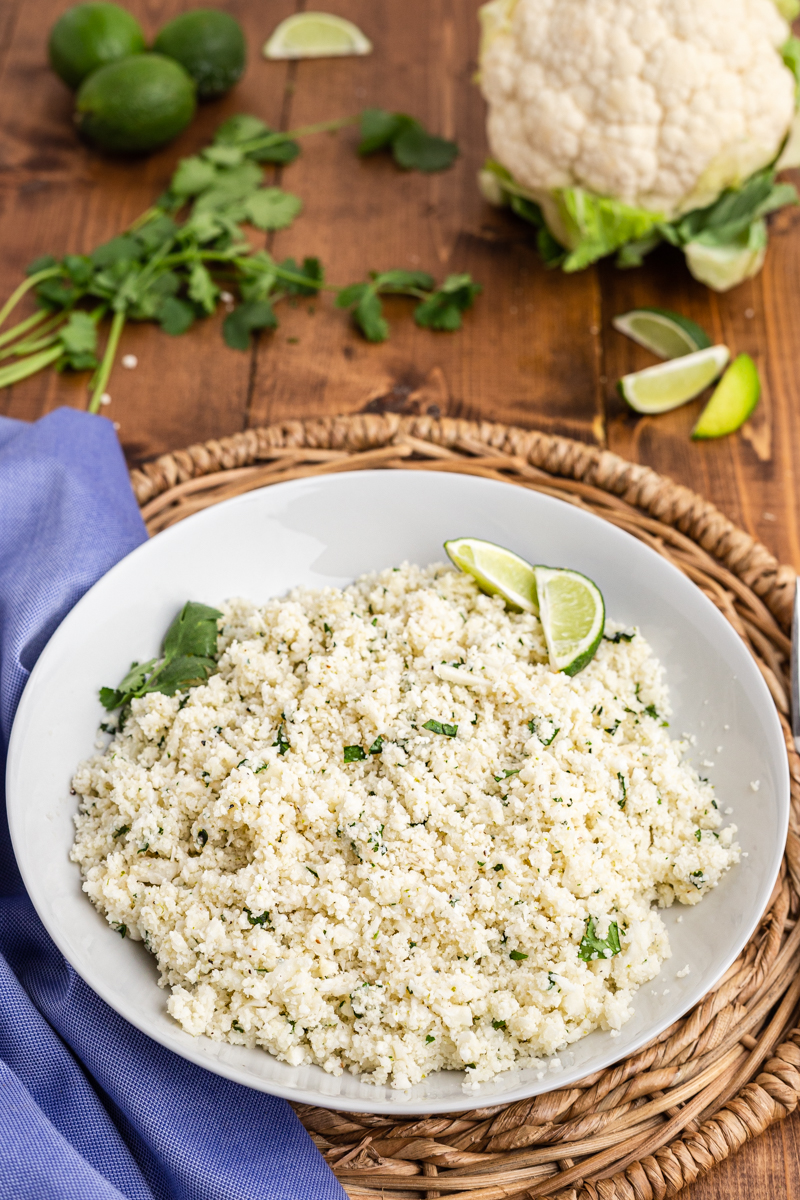 Photo of Copycat Chipotle Cilantro Lime Cauliflower Rice in a serving bowl on a wooden table.