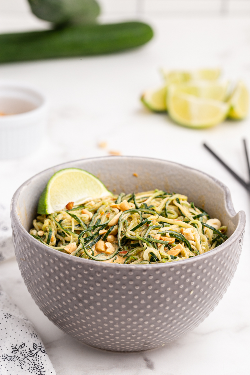 Photo of Spicy Peanut Cucumber Noodle Salad in a gray bowl with a lime wedge.