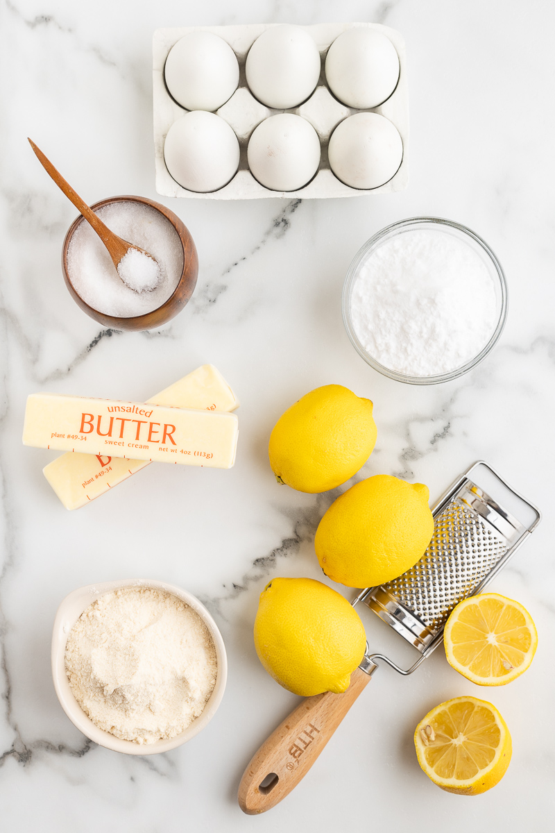 Overhead photo of the ingredients needed to make Keto Lemon Bars on a white marble countertop.