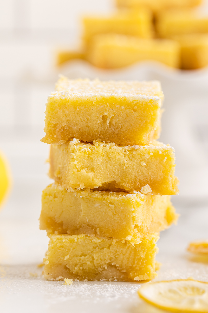 Closeup photo of a stack of four keto lemon bars on a white marble countertop.