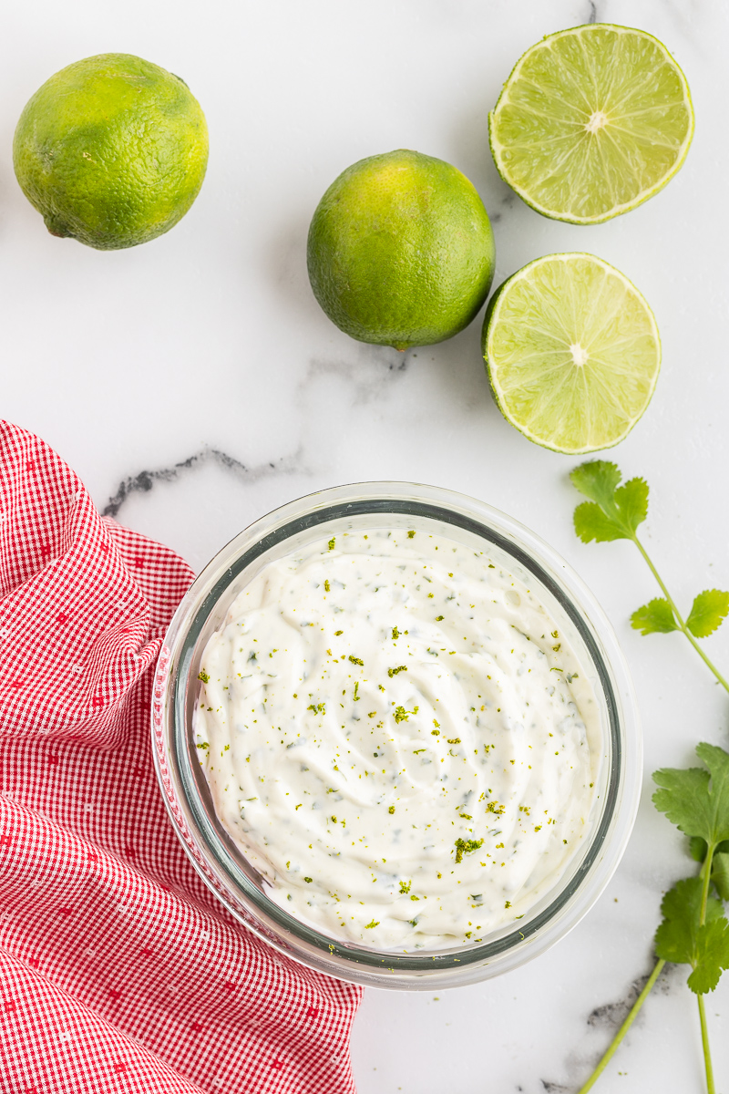 Overhead photo of Cilantro Lime Crema in a glass bowl on a white marble counter.