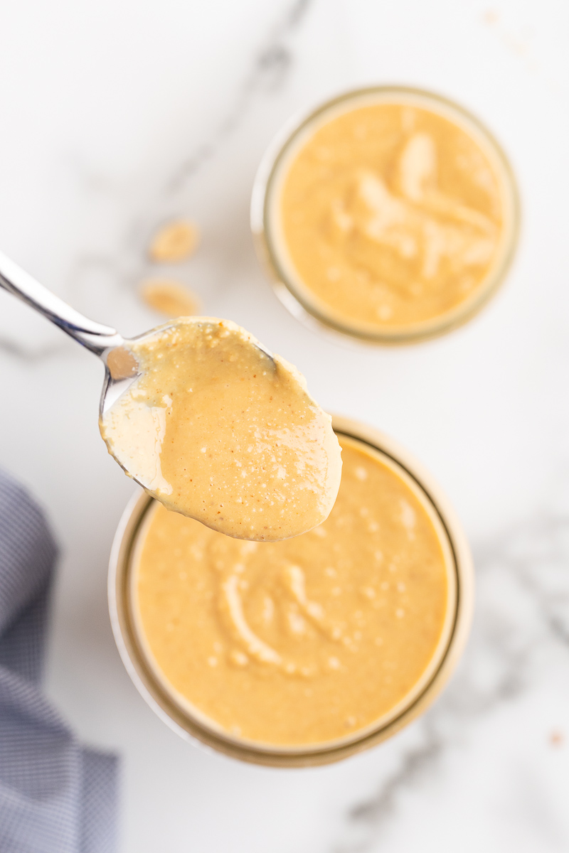 Overhead photo of Homemade Peanut Butter in a mason jar with a spoonful closer to the camera.