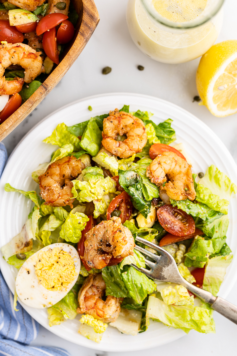 Overhead view of Low-Carb Shrimp Louie Salad on a white salad plate with a shrimp on the fork.