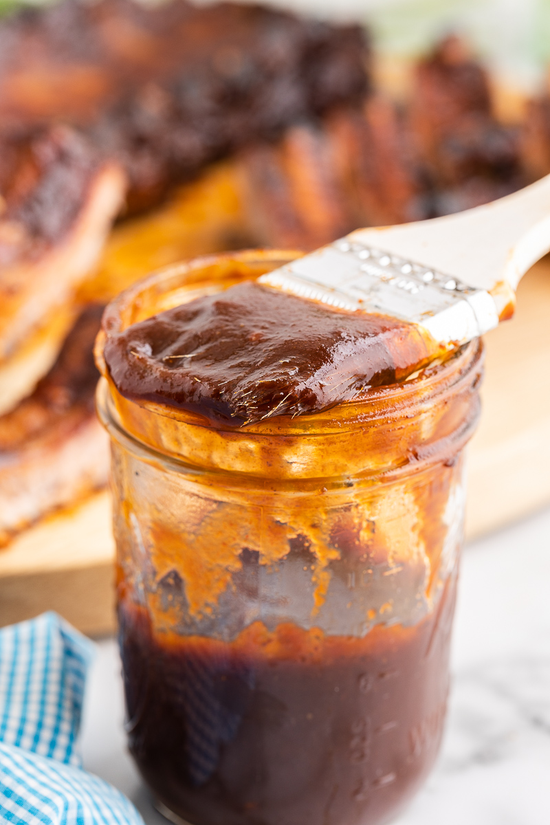 Mason jar with keto BBQ sauce in it and a brush on top.