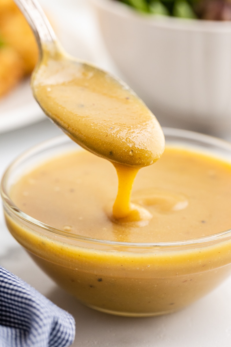 Sugar-free keto honey mustard sauce in a glass bowl with a spoon.