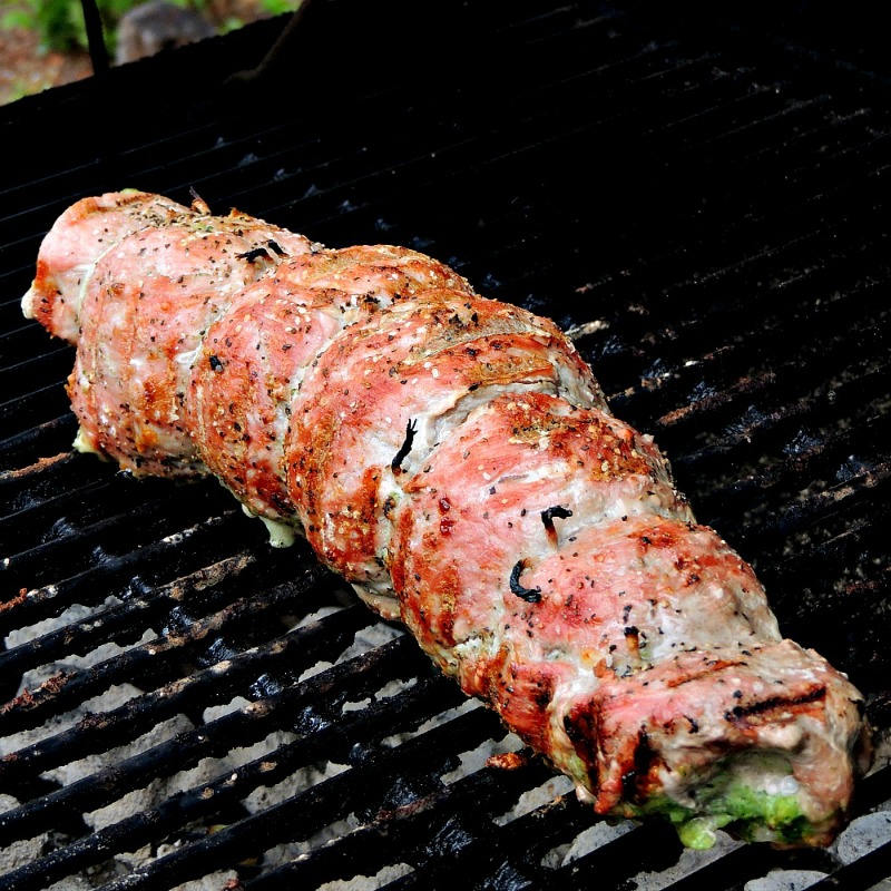 Broccoli Pesto and Cheese Stuffed Grilled Pork Tenderloin cooking on a charcoal grill.