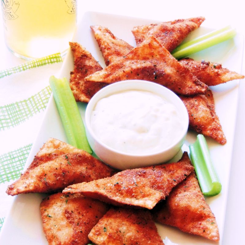 Buffalo Chicken Wontons on a white platter with a green and white towel in the background
