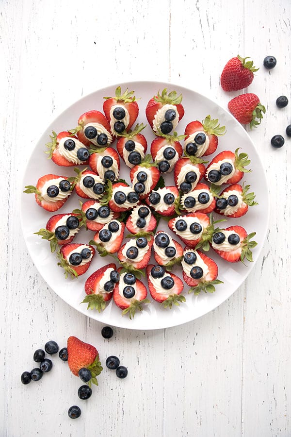 Overhead view of a white serving platter covered with Keto Cheesecake Stuffed Strawberries.