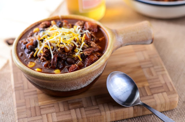 Crockpot Mexican Beer Chili in a brown bowl on a wooden cutting board