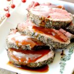 Beef Tenderloin Roast with Port Wine Cranberry Sauce sliced on a white serving tray.