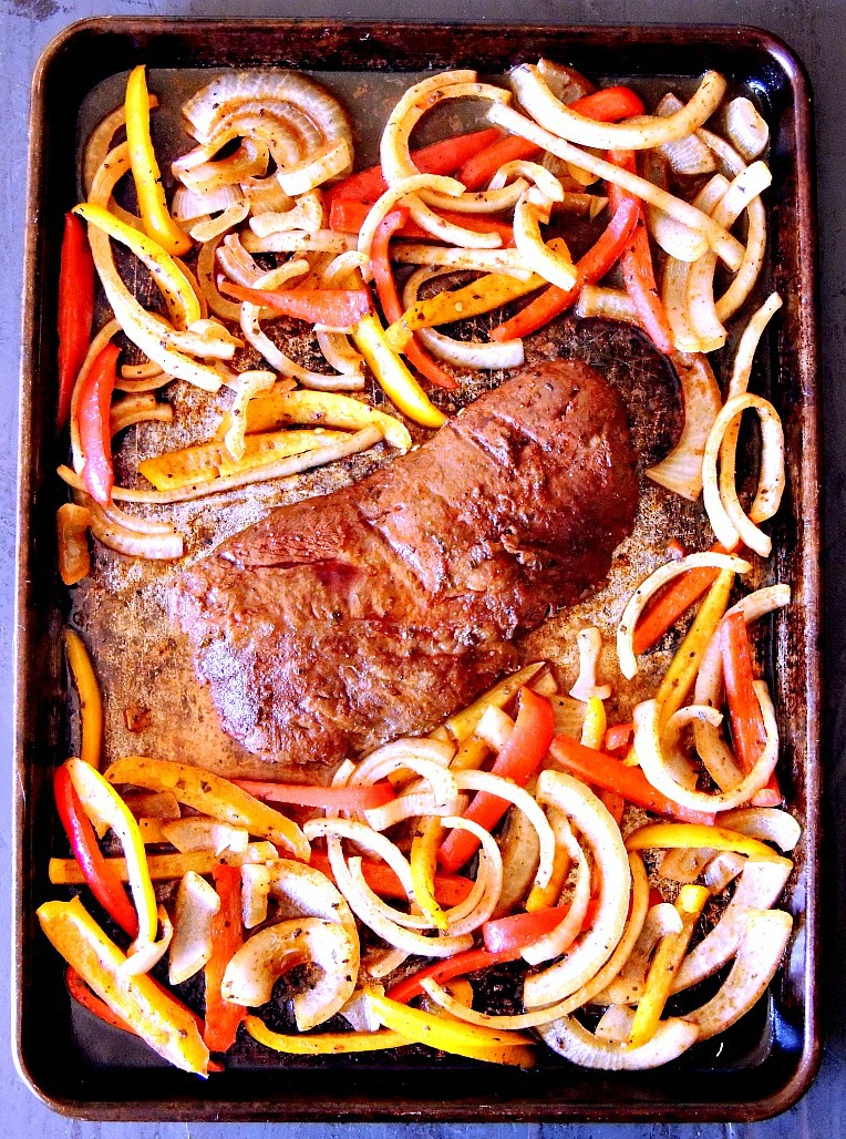 Overhead view of the steak and veggies on a sheet pan once they are cooked.