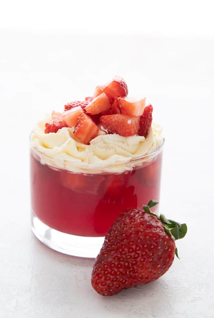 Easy Keto Jello in a glass dessert cup with chopped strawberries on top.