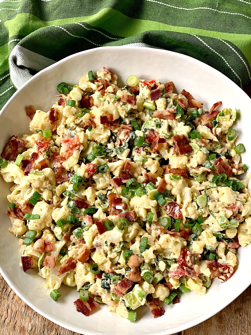 Close-up of a delicious and colorful BLT cauliflower salad in a large white serving bowl, featuring crispy bacon, fresh lettuce, and tender cauliflower florets, perfect for a healthy and flavorful low-carb or keto-friendly meal.