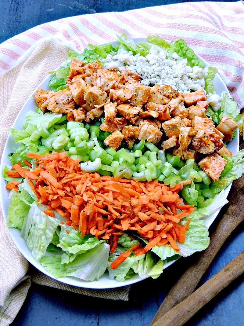 Buffalo chicken chopped salad layerd on a serving tray so you can see each ingredient. 
