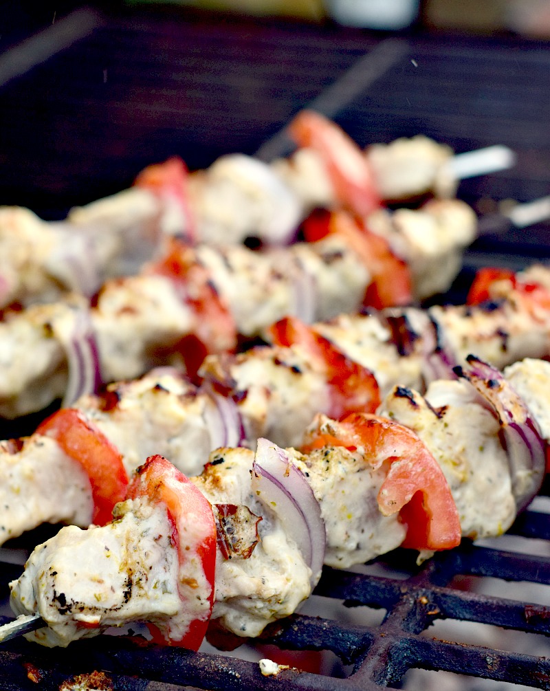 Kabobs with chicken, tomato, and red onion, charring on the grill.