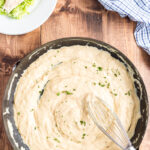 Low carb copycat Olive Garden Alfredo sauce in a skillet with a whisk on a wooden table.