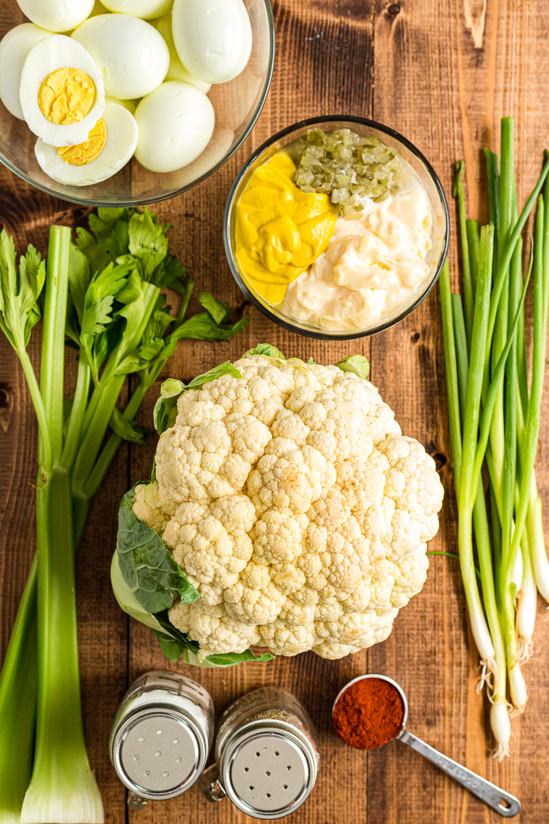 overhead view of the ingredients need to make deviled egg potato salad on a wooden table.