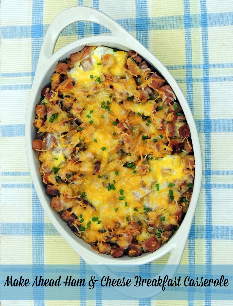 Overhead view of a Make-Ahead Ham and Cheese Breakfast Casserole in a white casserole dish on a blue and yellow plaid tablecloth. 