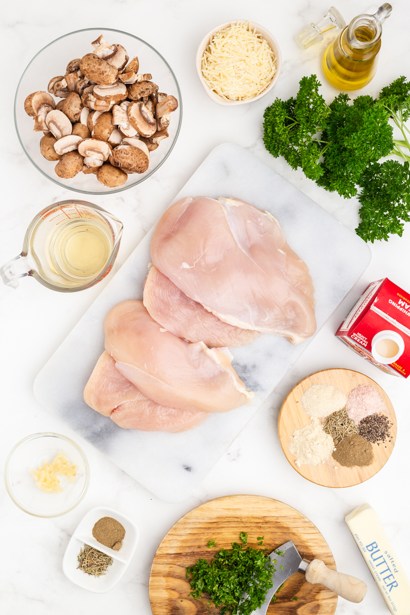 Overhead photo of the ingredients nedded to make Chicken with Mushroom Garlic Sauce on a white marble counter.