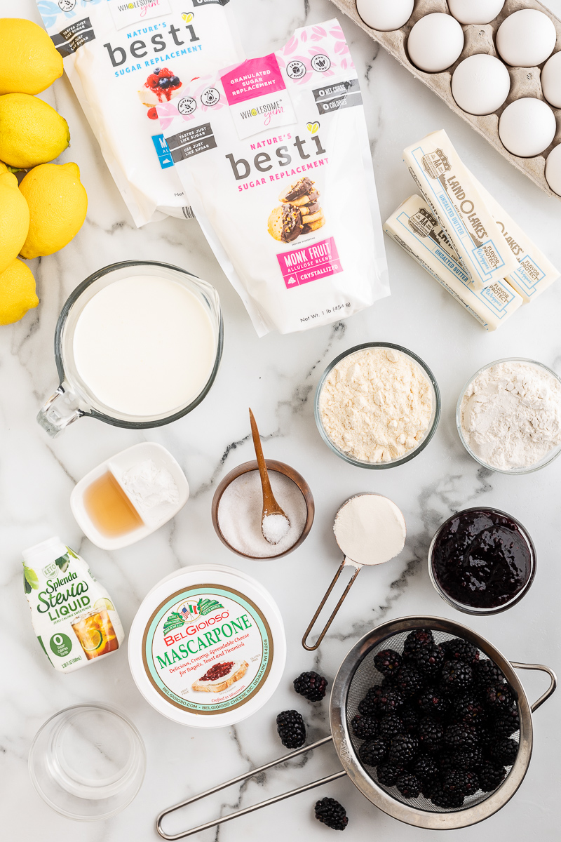 Overhead photo of the ingredients needed to make a Keto Lemon Cake with Blackberry Mascarpone Frosting on a marble counter.
