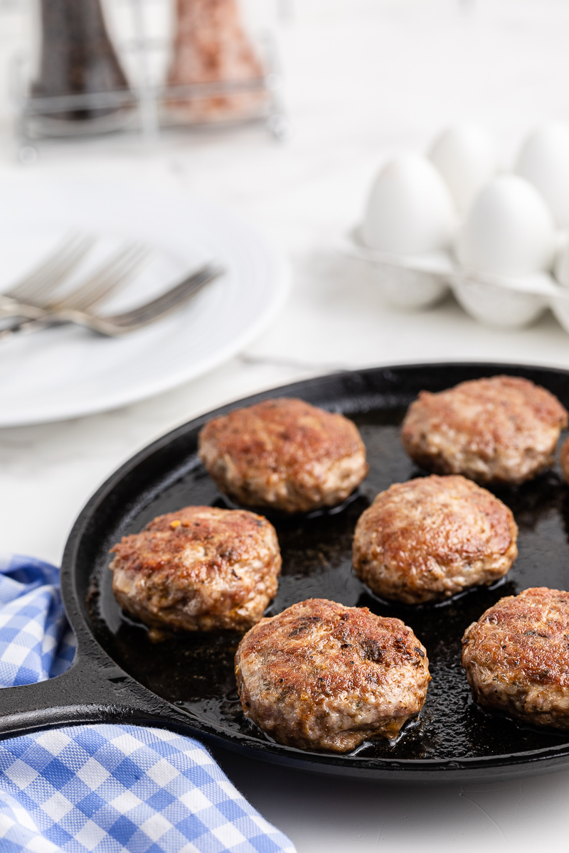 Cast iron skillet with homemade Keto Country Sausage patties cooking in it.